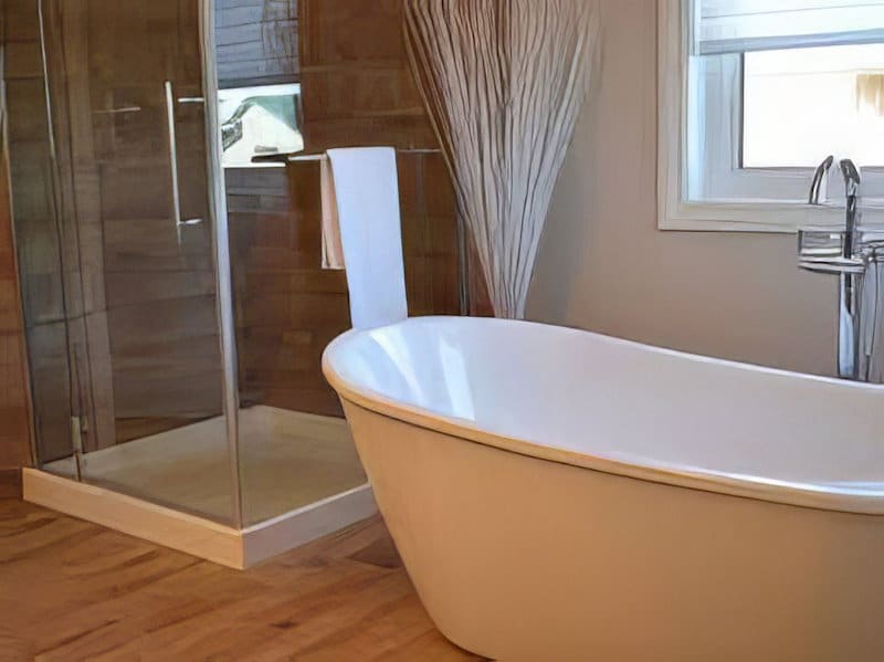 Белая ванна в ванной комнате с деревянным полом